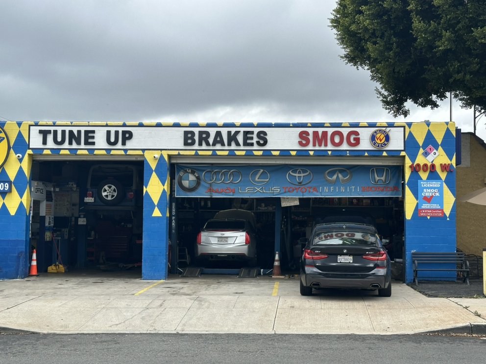Exterior of a blue and yellow auto repair shop offering tune-ups, brake service, and STAR certified smog checks for BMW, Audi, Lexus, and Toyota vehicles.